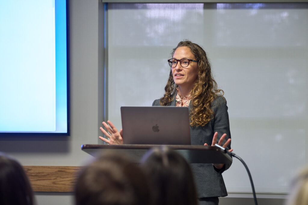 A woman stands at a podium presenting.